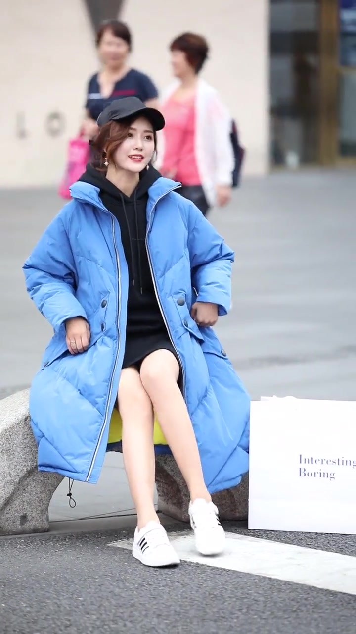 美女头戴鸭舌帽坐在石头上,棉袄搭配短裤,太好看了!