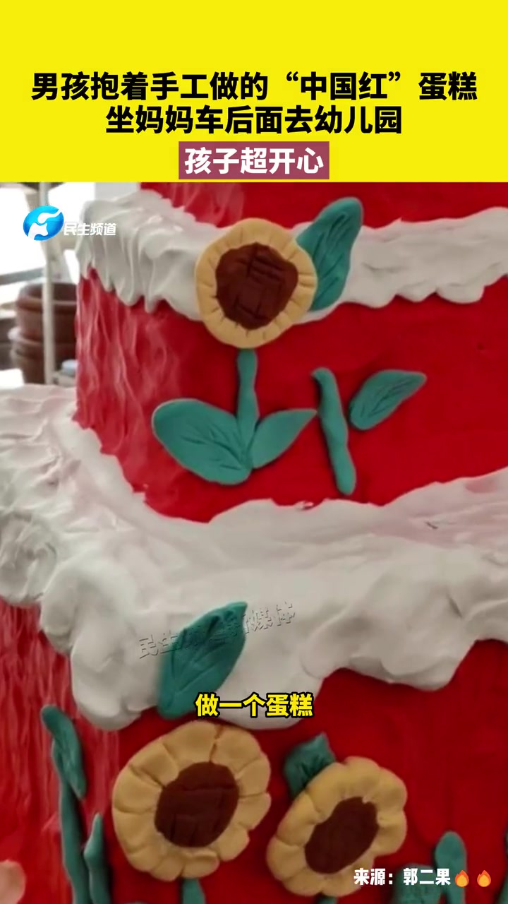 9月28日,山东枣庄,男孩抱着手工做的“中国红”蛋糕,坐妈妈车后面去幼儿园,孩子超开心 国