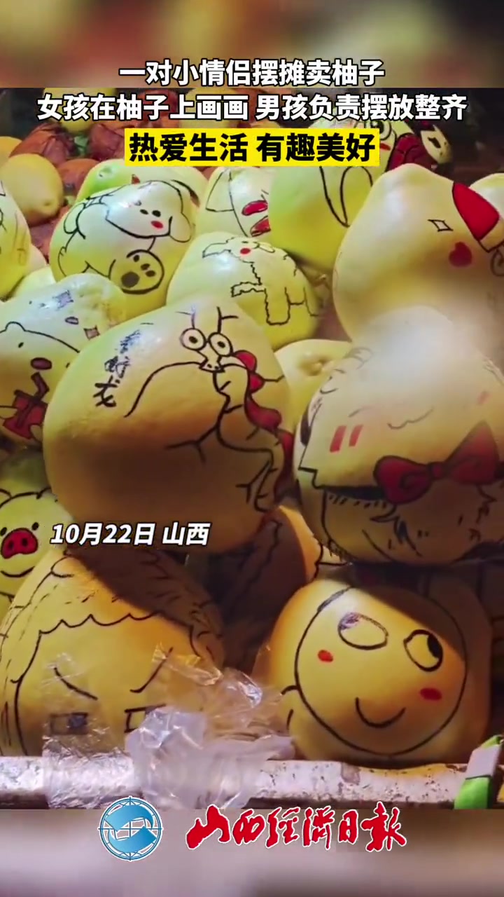 一对小情侣摆摊卖柚子,女孩在柚子上画画,男孩负责摆放整齐