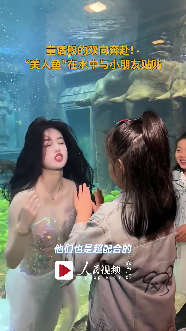 「美人鱼和小朋友互动画面唯美」1月18日,广西北海。海底世界的“美人鱼”表演结束后,在水中