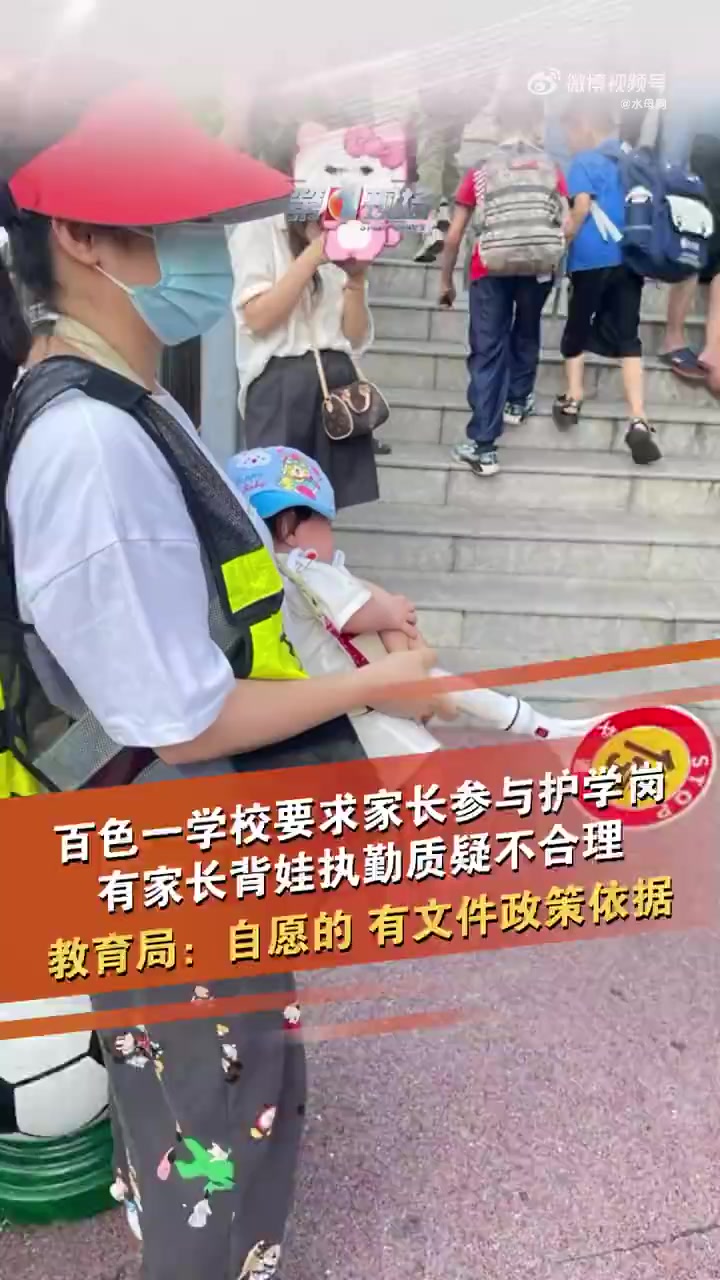 5月13日,广西百色右江区实验小学外,一名家长穿着反光背心,背着婴儿在校门口执勤护学岗近4