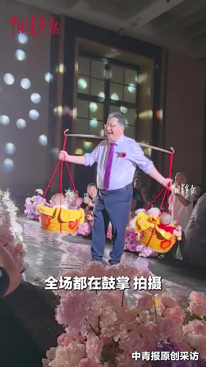 近日,浙江舟山,一对新人回家乡一起补办了婚礼和宝宝的百岁宴,爷爷用扁担挑着“龙凤胎”宝宝入