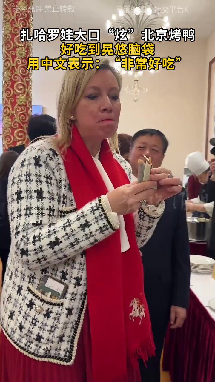 扎哈罗娃大口“炫”北京烤鸭 好吃到晃悠脑袋 用中文表示：“非常好吃”