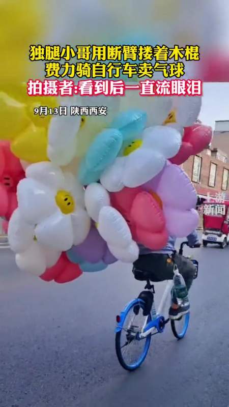 9月13日,陕西西安 独腿小哥用断臂搂着木棍费力骑自行车卖气球 拍摄者