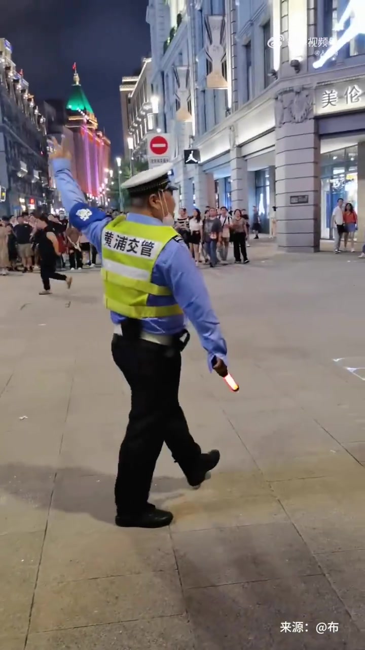 上海,一名交警在步行街路口,用幽默的方式指挥交通,引得路人阵阵欢笑