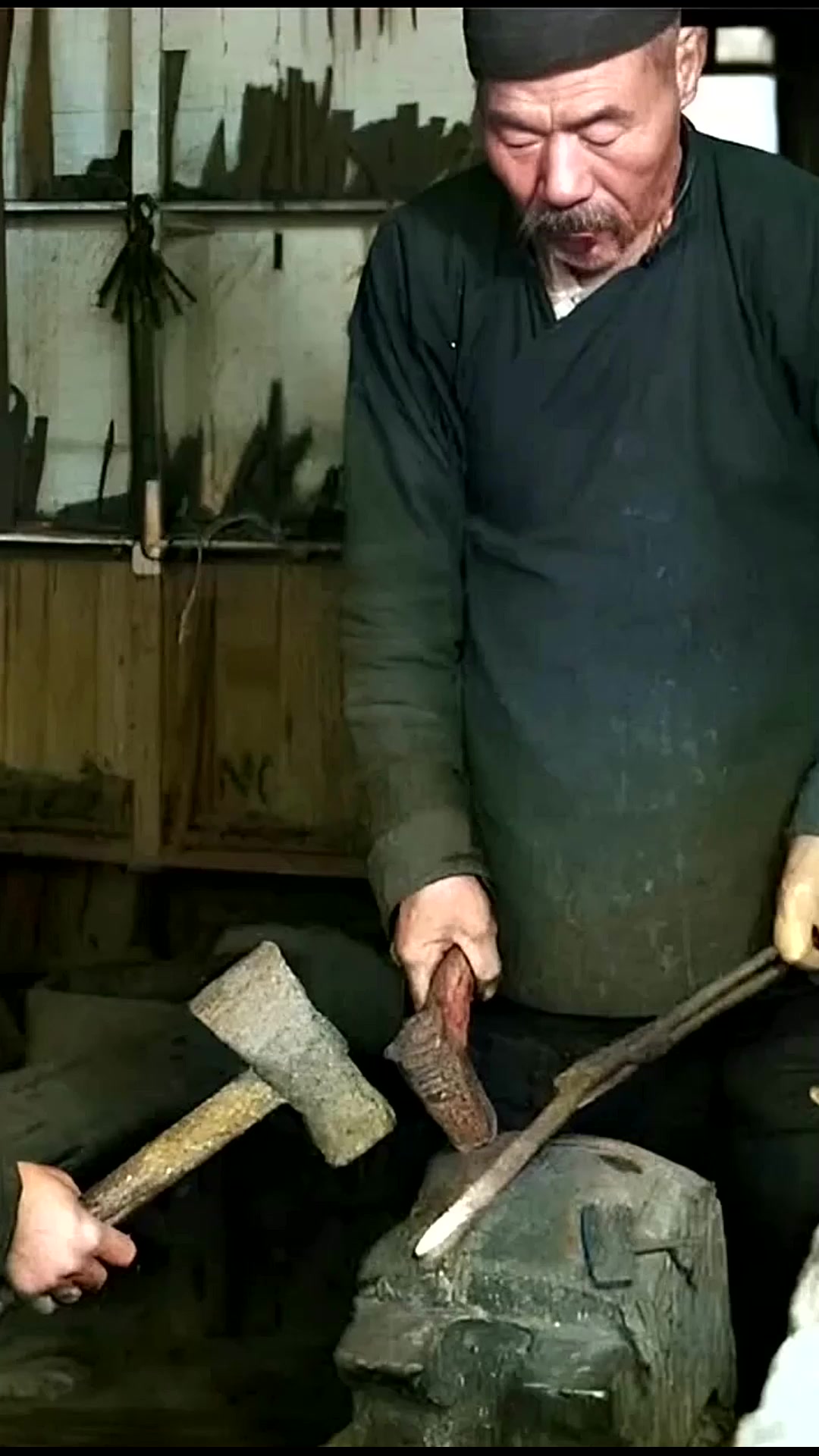 1930年代,铁匠铺里一名男孩抡起大铁锤帮助爷爷打铁