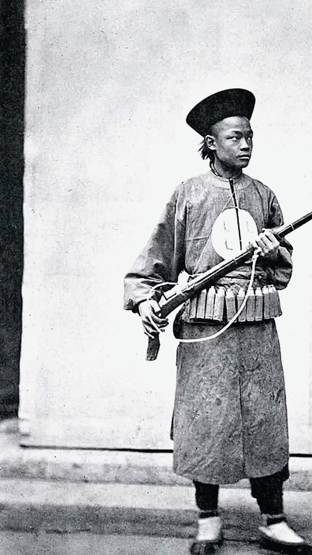 晚清时期,一位手持火绳枪的清军士兵照片,他的年纪不大,眼神挺